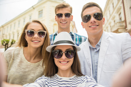 Double couple date. Friends walking down the street together and making selfie.