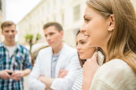 Four friends standing in the street and looking at something.の写真素材