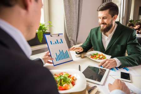 Two mature business people looking at chart at business lunch.の写真素材