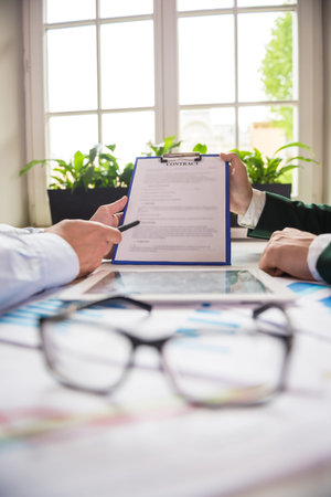 Close-up of male hands holding tablet and discussing the contract at office.