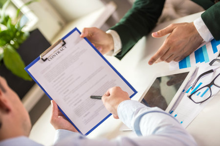 Close-up of male hands holding tablet and discussing the contract at office.
