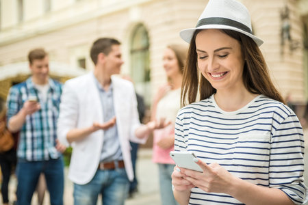 Beautiful girl dressed casual using phone while her friends waiting for her.の写真素材