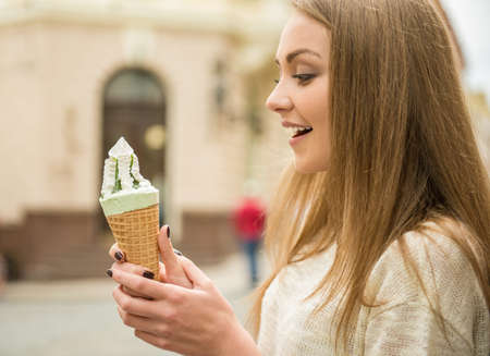 Young beautiful girl eating tasty ice-cream in the street.の写真素材