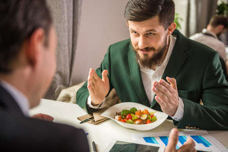 Two mature business people discussing the project at business meeting in cafe.の写真素材