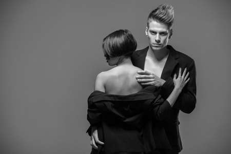 Young fashionable couple in tuxedos  posing in the studio. Black and white fashion portrait. Passion.の写真素材