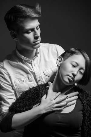 Young fashionable couple dressed casual posing in the studio on dark background. Black and white fashion portrait. Jealousy.の写真素材