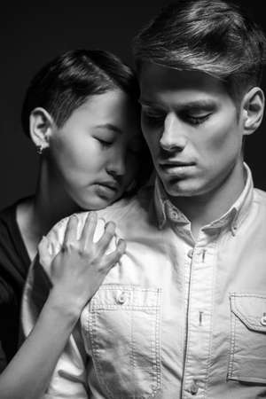 Young fashionable passionate couple dressed casual posing in the studio. Woman hugging man. Black and white fashion portrait.の写真素材