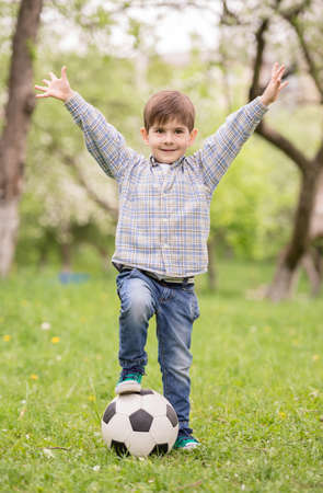 Little cute boy dressed casual playing with soccer ball in summer park.の写真素材