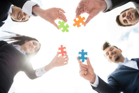 Closeup of business people wanting to put four pieces of puzzle together. Team work.の写真素材
