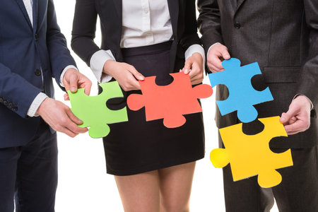 Close-up of business people wanting to put pieces of puzzle together.の写真素材