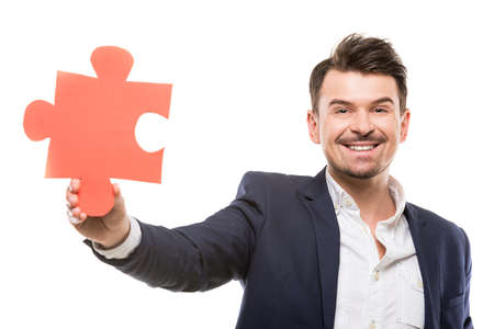 Handsome businessman showing a piece of jigsaw puzzle, over white background.の写真素材