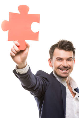 Handsome businessman showing a piece of jigsaw puzzle, over white background.の写真素材