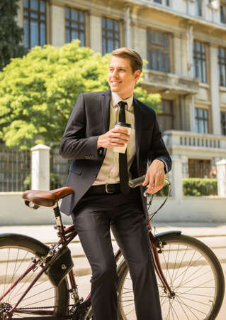 Portrait of young businessman riding bicycle to work on urban street.の写真素材