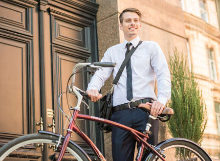 Young handsome office worker going to work on his bicycle. Healthy lifestyle concept.の写真素材
