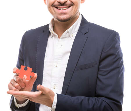 Close-up of businessman showing small jigsaw puzzle over white background.の写真素材