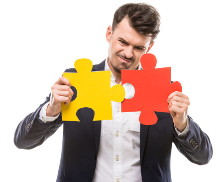 Handsome man in suit trying to connect puzzle pieces.の写真素材