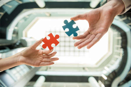 Close-up of business people wanting to put two pieces of puzzle together.の写真素材