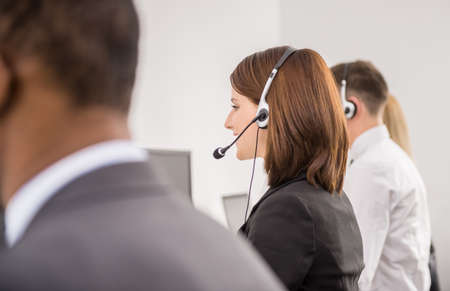Call centre workers working in line with their headsets. Back view.の写真素材
