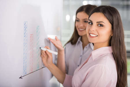 Two beautiful office workers drawing business strategy concept.の写真素材