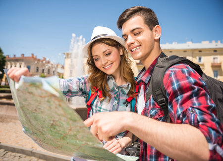 Young tourist couple consulting the map on a sunny day in the city.