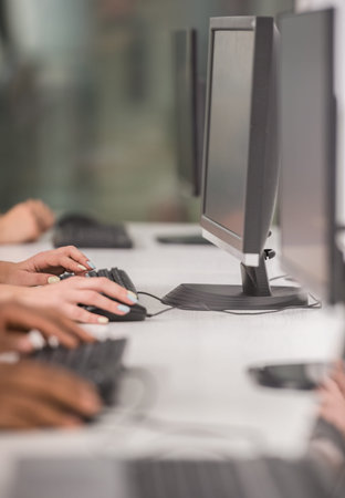 Close-up of office workers sitting at the table in office and using computers.