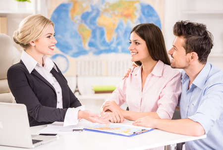 Beautiful woman sitting at office with clients and proposing hot tours to them. Beautiful woman sitting at office with clients and proposing hot tours to them.
