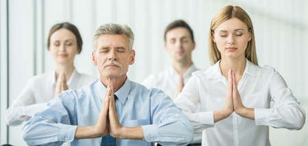 Businesspeople meditating in office, hands put together, concentrating.の写真素材