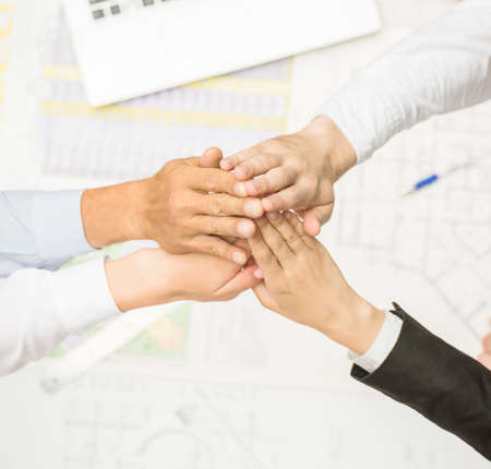 Four architects sitting around a table and putting hands together. Close-up.の写真素材