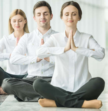 Businesspeople meditating in office, hands put together, concentrating.の写真素材