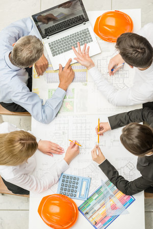 Team of architects working on construction plans at design office.