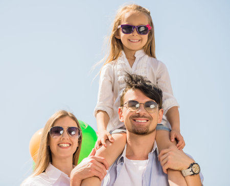 Young family with colorful balloons walking on sunny day.の写真素材