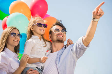 Happy family with balloons looking up outdoor on a summer day.の写真素材
