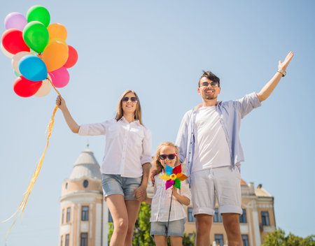 Happy family holding colorful balloons outdoor. Mom, dad and little daughter playing together.の写真素材