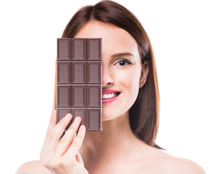 Beautiful woman closing half of face with bar of chocolate.