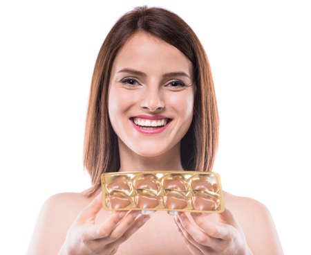 Cheerful young woman holding delicious chocolate candies over white background.の写真素材