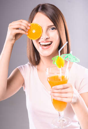 Beautiful  playful woman with bright cocktail over gray background. Studio shot.の写真素材