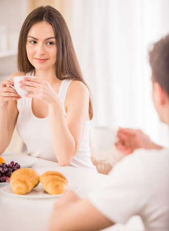 Young woman sitting at the table in kitchen and drinking tea for breakfast.の写真素材