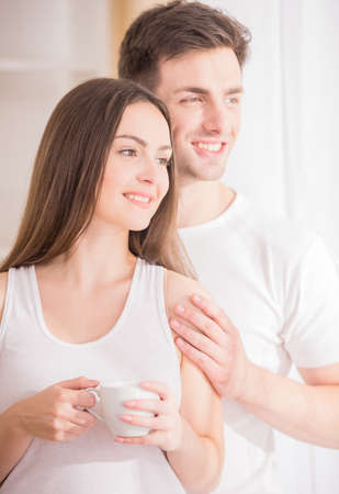 Image of cheerful couple looking at the window at home and dreaming about beautiful life.の写真素材