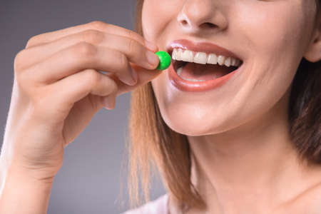 Beautiful woman enjoying chocolate drop over  gray background. Close-up.の写真素材
