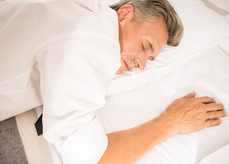 Businessman sleeping on bed after hard working day at the hotel room.の写真素材