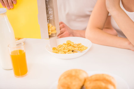 Young family couple sitting at the table in the kitchen and preparing breakfast together. Close-up.