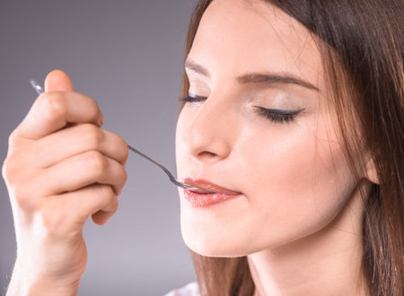 Beautiful woman enjoying dessert with closed eyes over gray background.の写真素材