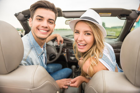 Couple in love sittling on the cabriolet and looking at camera. Back view.の写真素材