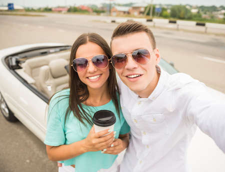 Young beautiful couple in sunglasses taking selfie against cabriolet.の写真素材