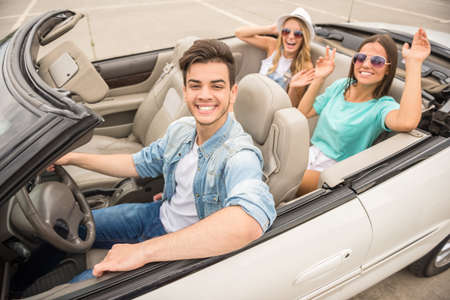 Three happy friends traveling in the cabriolet. Two girls having fun on rear seats.の写真素材