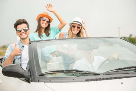 Group of friends in sunglasses traveling on the cabriolet and having fun.の写真素材