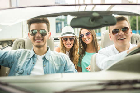 Group of happy friends in sunglasses traveling on the cabriolet. Front view.の写真素材