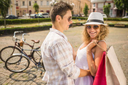 Couple in love hugging on the city square. Woman holding shopping bags and looking at camera.の写真素材