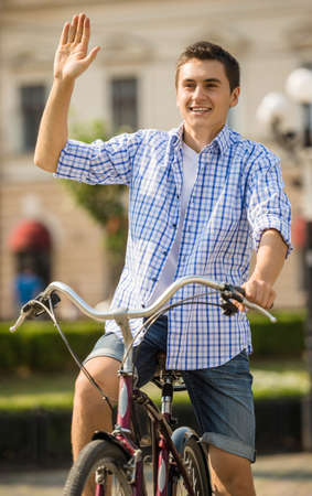 Young man riding on bicycle in the city street in summer day.の写真素材