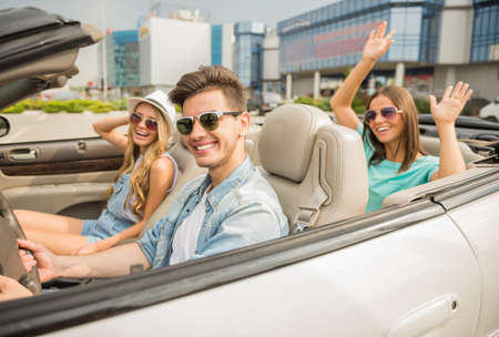 Adorable car trip on vacation. Group of happy friends driving by cabriolet.の写真素材